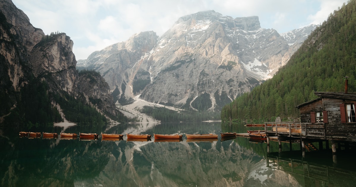 Photo: alpine lake reflecting wooden cabins in the Dolomites