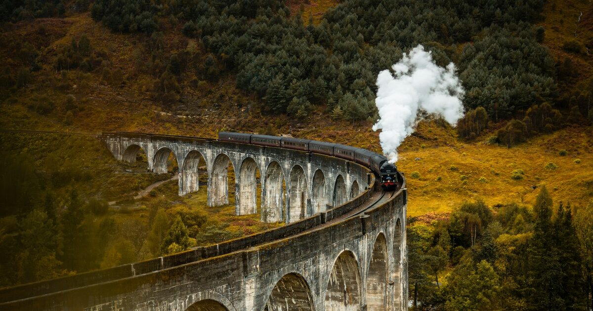 Photo: Glenfinnan viaduct with steam train crossing Scottish highlands